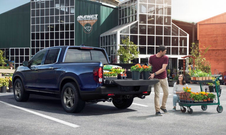 Person loading plants into the bed of a 2022 Honda Ridgeline parked by a garden center